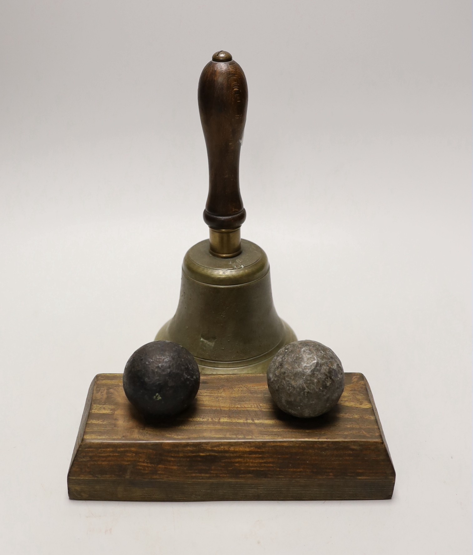 Two cannon balls, together with a brass hand bell marked A.R.P